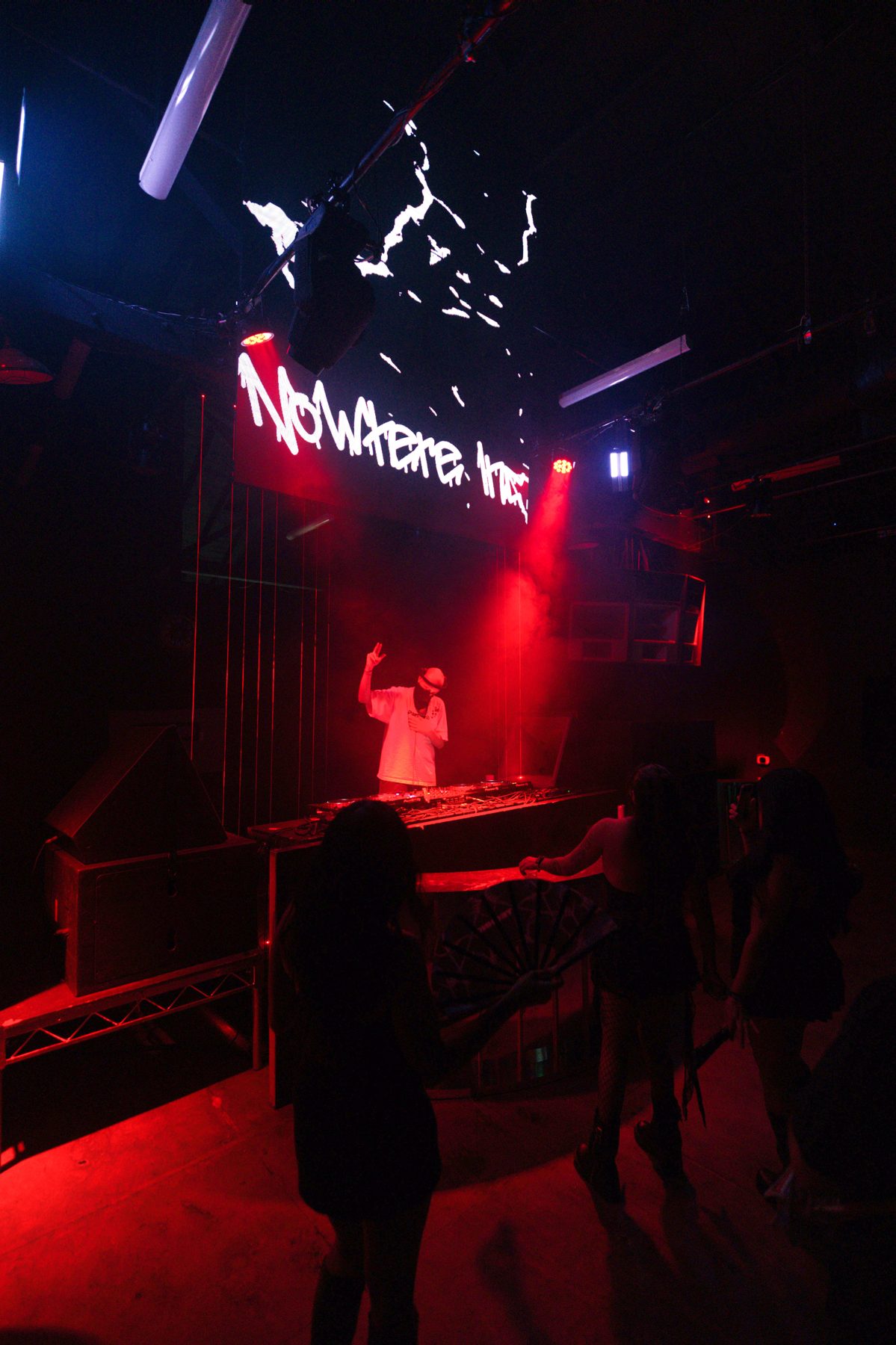 NOWHERE INC. performing on stage beneath a projected wordmark, red stage light